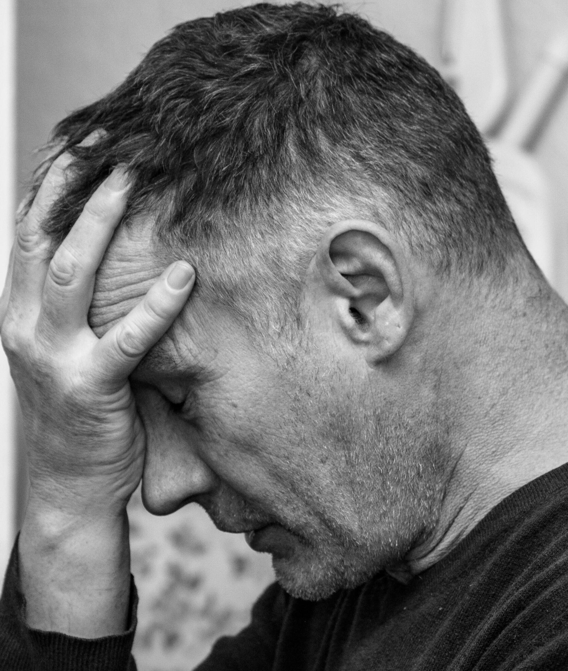 A man sitting with his head resting in his hand, looking overwhelmed